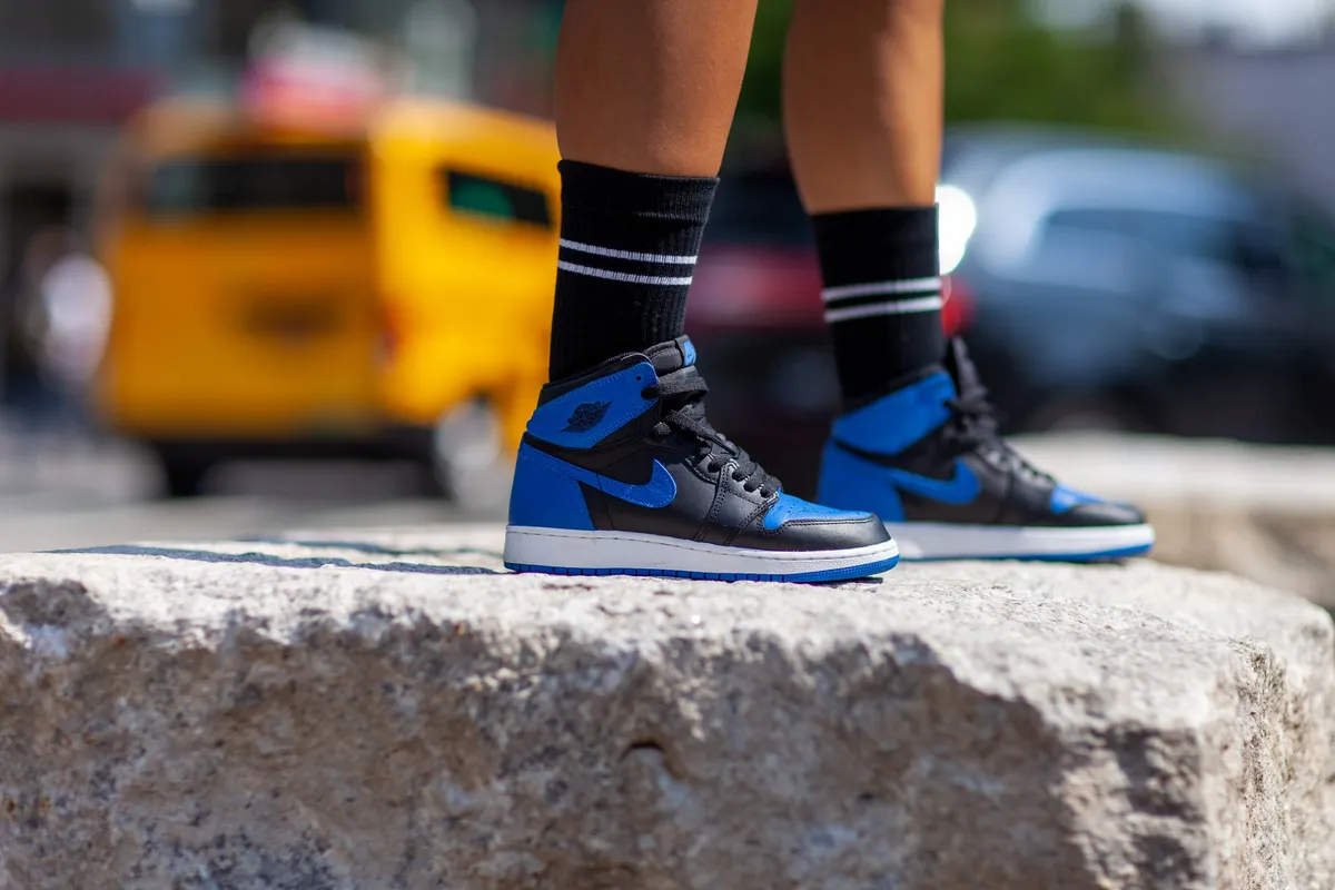 Detail of blue and black sneakers on a granite block with a yellow taxi blurred behind