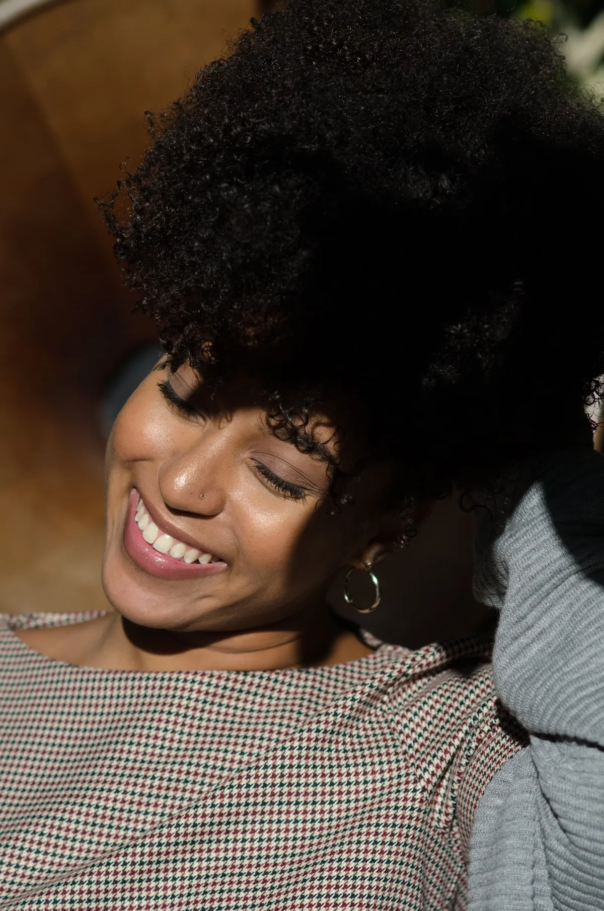 A woman laughs with her head tilted, curls catching the late afternoon sun